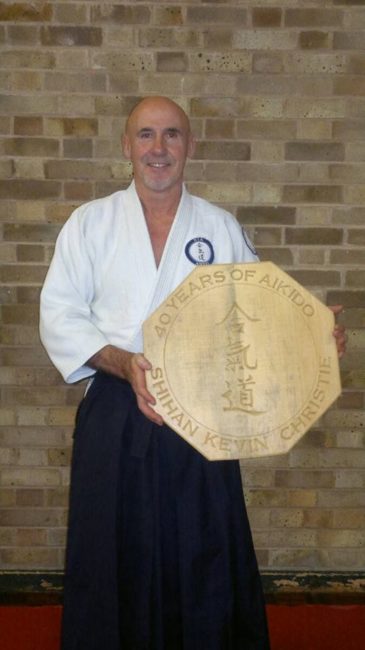 Shihan Kevin Christie with a carved wooden plaque given to him by Nia Aikido students and dan grades for his 40 years in Aikido